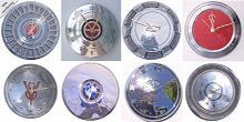 Vintage auto hubcaps recycled into wall clocks with numbers including VW, Benz, BMW, etc.